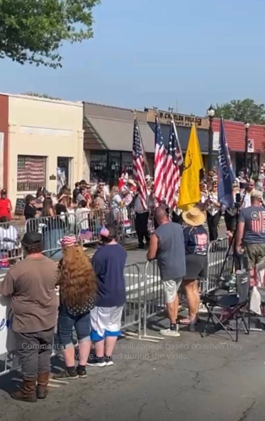 A wider view of flag bearers and spectators along the downtown parade route.