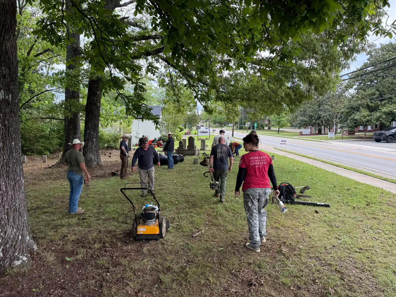 Volunteers and lawn equipment at Jasper City Cemetery beside Church Street.