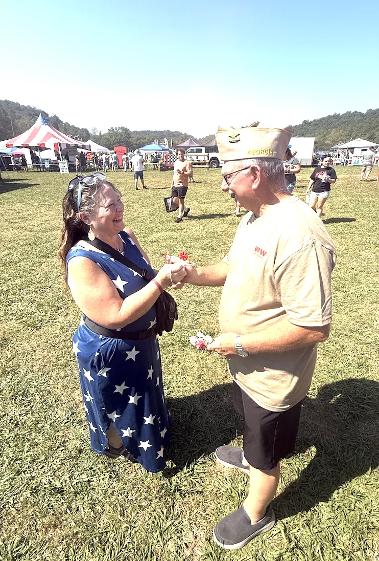 David Petty hands a red Buddy Poppy to a smiling visitor at JeepFest.